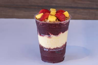 Layers of Paradise - Two layers of açaí base in the flavor of your choice, with a creamy passion fruit layer in the middle. It comes with granola between the layers and two fruits of your choice on top.